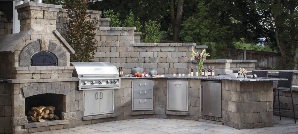 Outdoor stainless steel kitchen with stonework.